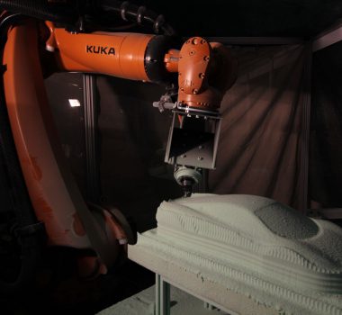 A robot arm machining a foam block.